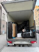 Flyttbil lastad med inplastade möbler och säng inför en flytt mellan städer.
