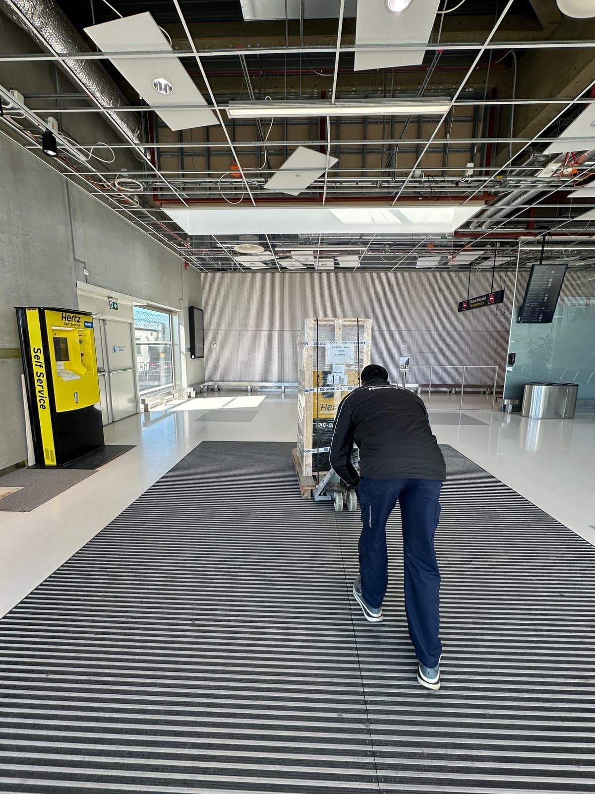Nordflytt-medarbetare drar en kiosk på palldragare genom en terminalbyggnad på Bromma flygplats