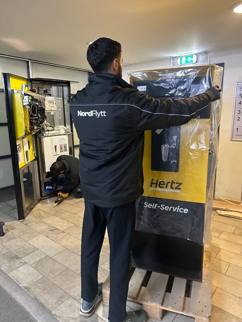 Nordflytt-medarbetare tar plasten av en ny Hertz self-service-kiosk som står på pall