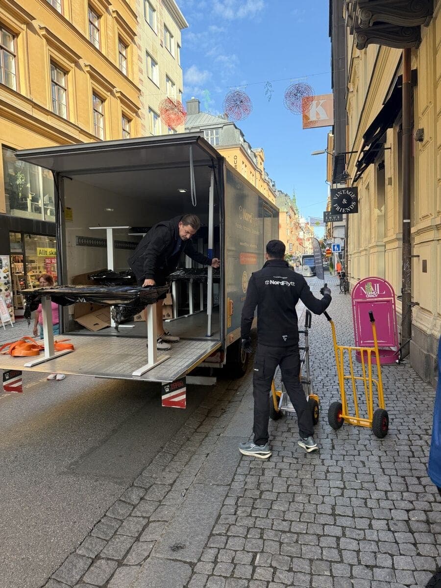 Nordflytts team lastar emballerade skrivbord vid lastbilens bakgavel under Strongers flyttdag